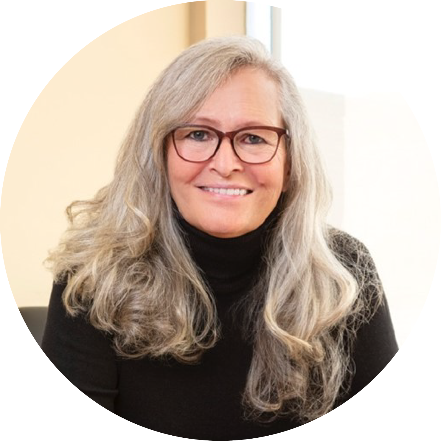 Woman with long silver hair, brown glasses and black turtleneck